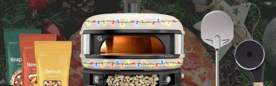 photo of a gozney pizza oven deocrated with colorful christmas lights, also featuring gozney's line of pizza dough flours